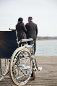 Rollstuhl plus Mann und Frau im Hintergrund